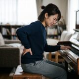 ピアノ演奏で腰が痛い原因は?理学療法士が教える姿勢の崩れと改善セルフケア 9 腰痛でピアノ演奏を前にして苦痛を感じている女性の様子
