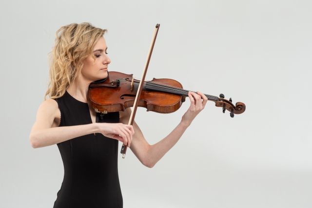 演奏姿勢において比較的負担の少ない姿勢を保っているバイオリン演奏車の女性の写真です。上半身の正面に対して60〜70°程度が理想ではと感じています。