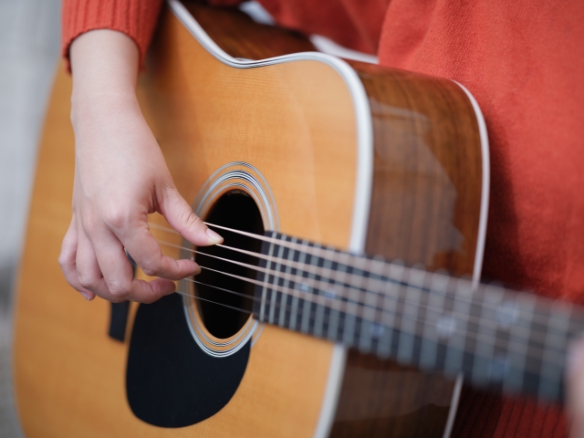 ギター演奏中の写真です。指を繊細に扱う楽器であるため、指の動きに関わる筋肉や疲労がパフォーマンスに大きく関わります。