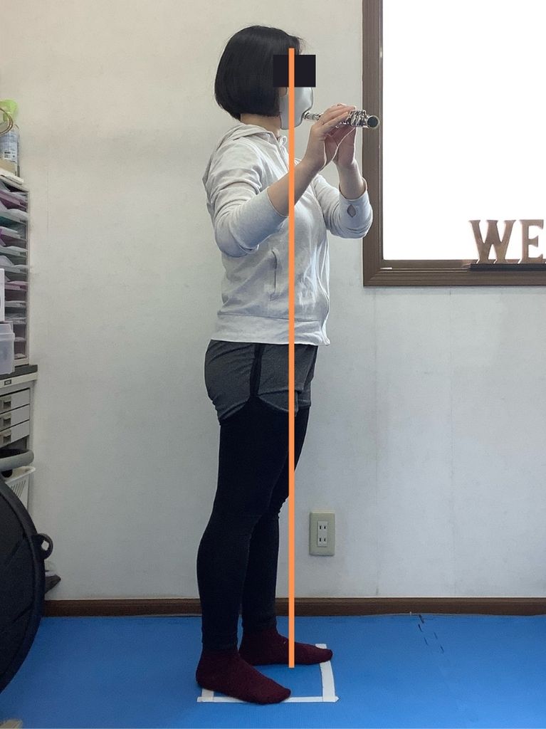 前方重心でのフルート演奏姿勢を保持している写真です。息の吸いづらさや首・肩の張り・腰痛などが起きやすくなります。