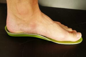 中敷き(インソール)に足を載せている写真です。外反母趾の場合、親指の付け根の部分と小指の付け根の部分の足幅が中敷きと自分の足とが一致するように使うといいです。
