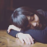 睡眠不足で机で寝てしまっている女性