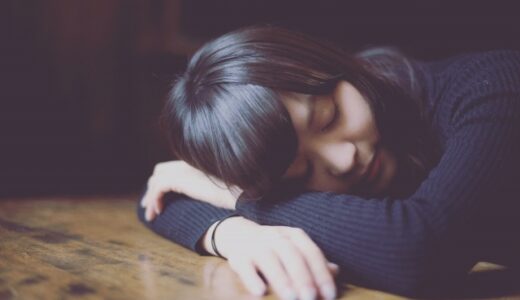 睡眠不足で机で寝てしまっている女性