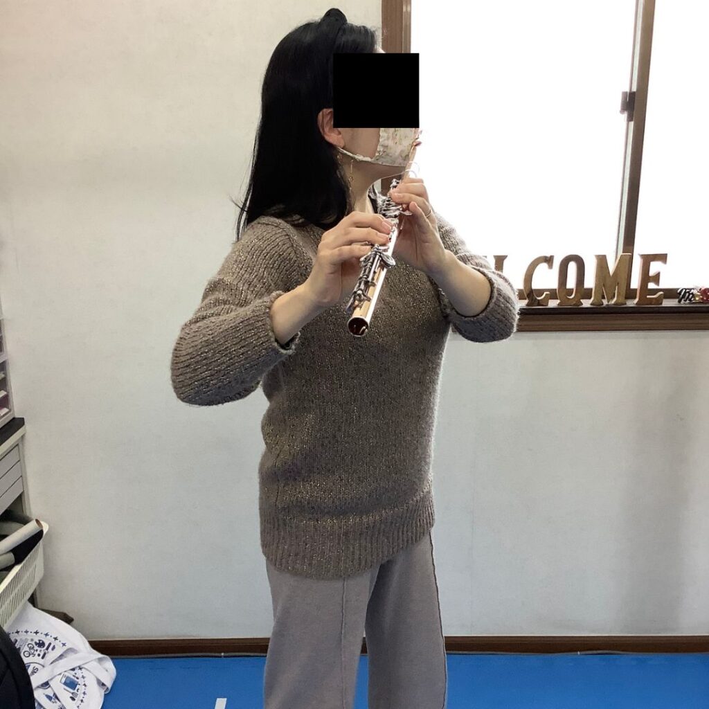 フルート奏者で肩の後ろ側の痛みが出ていた症例。巻き肩に加えて上腕骨頭前方偏位があり、フルートを構える際に肩関節が屈曲せずに伸展してしまっている。
