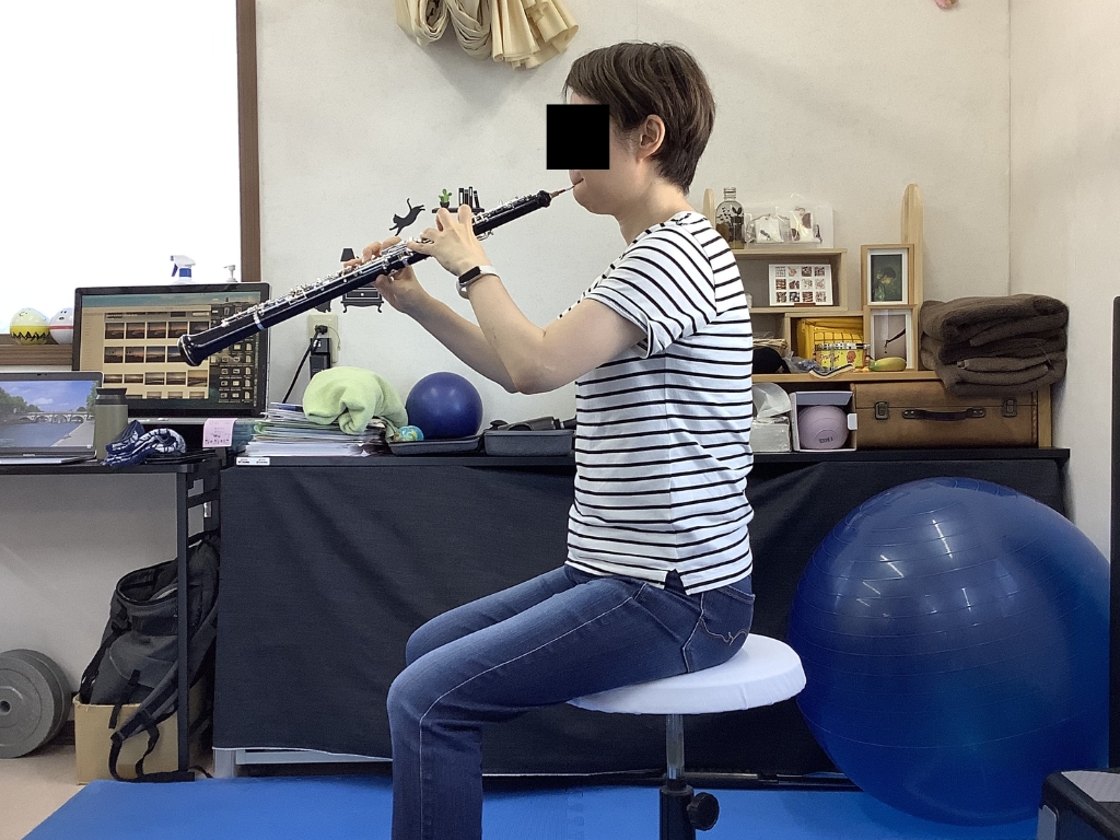 オーボエ奏者の悪い姿勢を移した写真。猫背・巻き肩になり、脇を開いた状態で、オーボエが身体から60度程度上がっている。