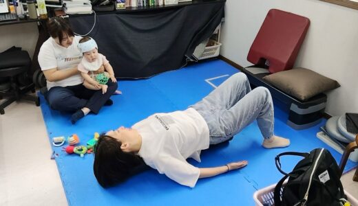 見守りスタッフがお子さんを抱っこしている横でストレッチポールでのエクササイズを行うママの様子